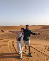 Akshat and Akanksha on the dunes at Merzouga in the Moroccan Sahara, a camel train behind them